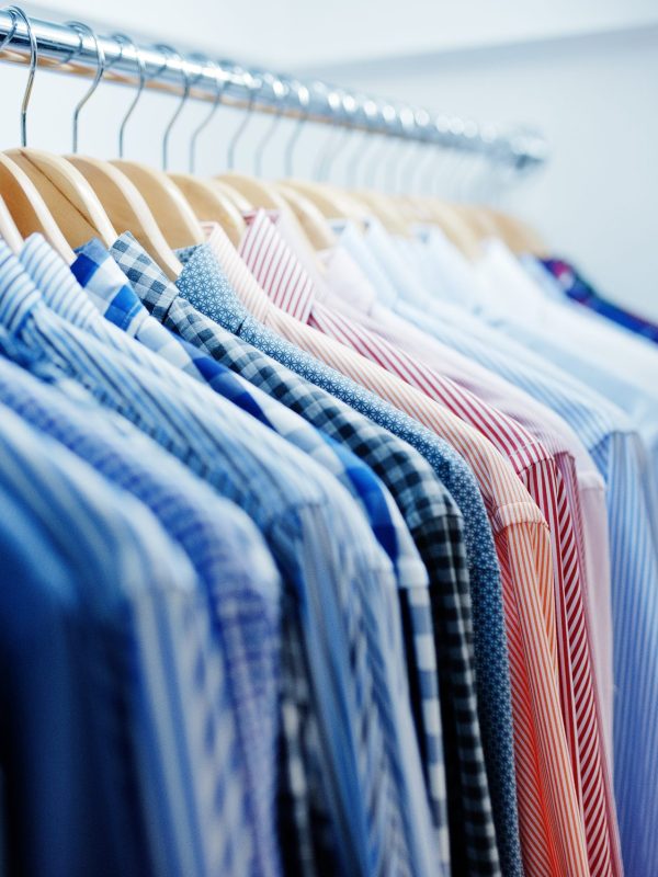Close-up photo of fashionable clothes on hangers in the shop.